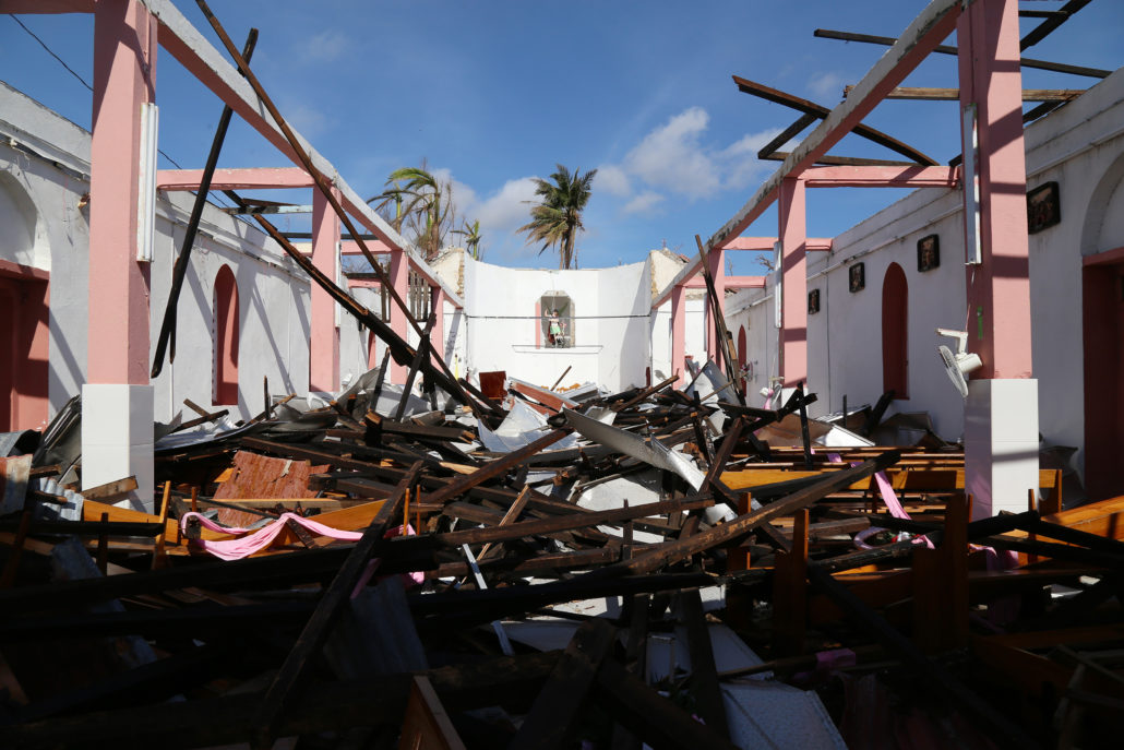 Una estatua protegida en un nicho es todo lo que queda de pie en esta iglesia católica en la ciudad costera de Roche Bateau, Haití. La iglesia se encuentra entre miles de edificios y viviendas que fueron destruidas por un huracán de categoría cuatro el 4 de octubre. El huracán Matthew azotó los pueblos a lo largo de la península de Tiburón, en el suroeste de la costa de Haití, también conocida como el granero de Haití. Lluvias torrenciales y vientos de 233 kilómetros (145 millas) por hora derribaron árboles, arruinaron cosechas, arrastraron a personas y animales, y destruyeron hasta el 90 por ciento de los hogares en algunas zonas. Más de 2 millones de personas, aproximadamente la población de Houston, TX, se vieron afectadas, cientos de personas murieron y 1.4 millones de hombres, mujeres y niños necesitan ayuda de emergencia. No es sólo la costa que está padeciendo. La pérdida de cultivos pone en riesgo el bienestar de todo el país debido a que la zona es un productor clave del suministro de alimentos de Haití. El agua limpia es escasa y el saneamiento deficiente amenaza con desencadenar otro brote de cólera, una enfermedad que ha cobrado la vida de unas 10,000 personas desde el terremoto de 2010. Catholic Relief Services y socios locales de la Iglesia están jugando un papel fundamental para hacer frente a las necesidades de la comunidad y han estado en el sitio desde el primer día proporcionando suministros esenciales, como alimentos, mantas y otros suministros de emergencia. Para obtener más información, visita: crsespanol.org Foto de Marie Arago for Catholic Relief Services