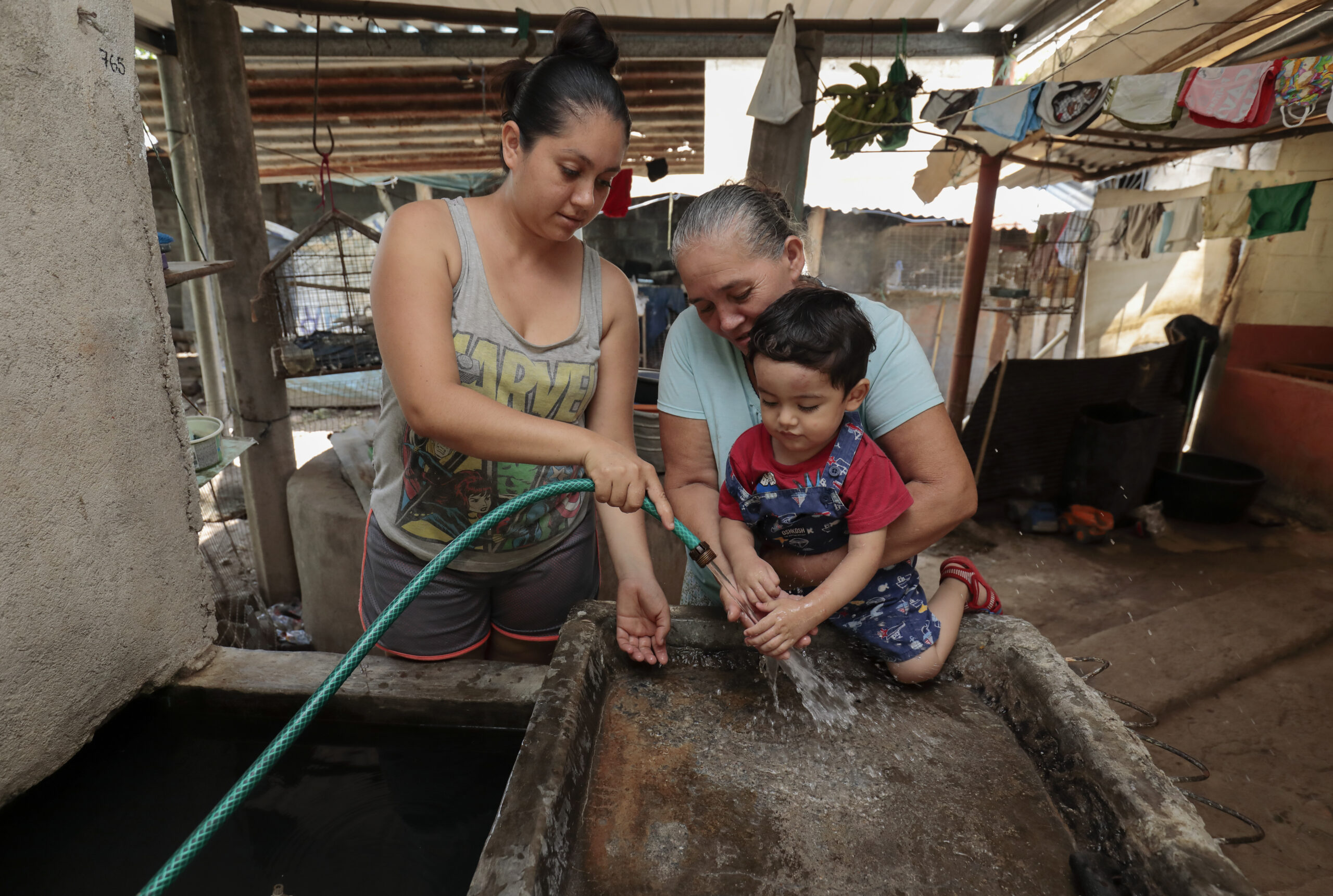 dos mujeres lavan las manos de un pequeño