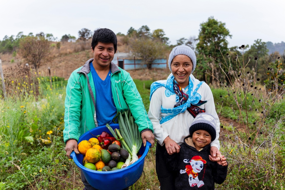 familia de agricultores muestra los vegetales que cosecharon