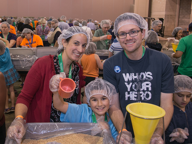 familia voluntaria de CRS empaca alimentos